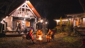 A log cabin with a balcony, a fire pit, and a deck area. - Log Cottage Chausu no Mori (Nasu)