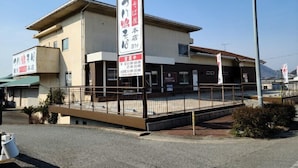 A two-story building with a covered outdoor seating area and multiple signs indicating business hours. - Business Hotel Nishiwaki (Nishiwaki)