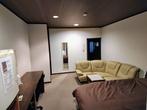 Une pièce avec un canapé en cuir beige, une petite table, un tableau blanc et une porte.