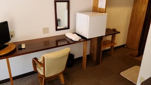 A compact hotel room with a wooden desk, a small chair, a white refrigerator, a mirror, and a coat rack. - Business Hotel Nishiwaki (Nishiwaki)