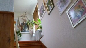 Una escalera de madera con barandilla que lleva a un rellano con un cuadro de flores enmarcado en la pared.