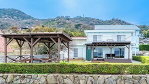 A two-story house with a covered patio and a stone wall in front. - Sea Side Villa Kamano (Takamatsu)