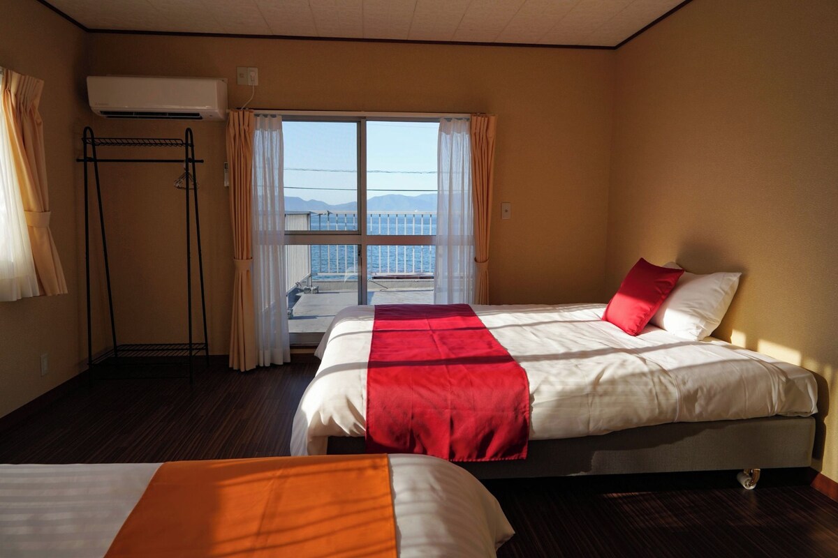 A hotel room with two beds, a balcony with a view, and an air conditioning unit.