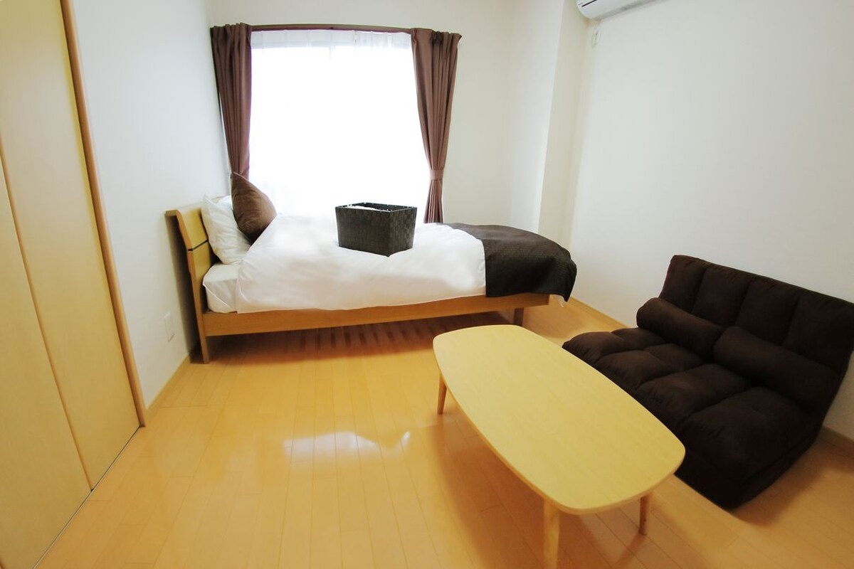 A small, modern room with a bed, a sofa, and a small table.
