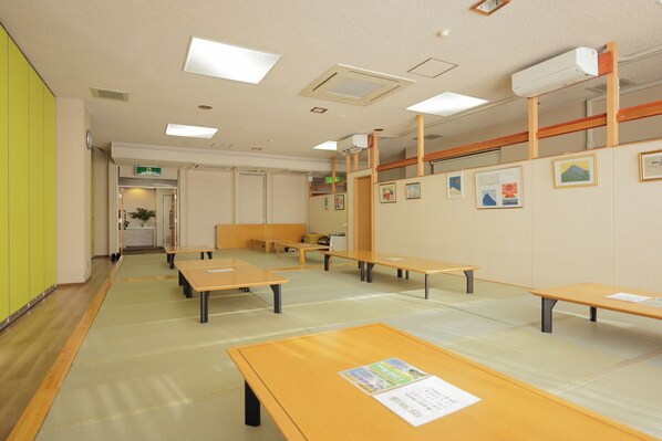 A room with multiple tables and benches, a ceiling with recessed lighting, and artwork on the walls.