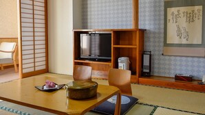 A traditional Japanese-style room with tatami flooring, a low wooden table, a television, and a shoji screen. - Kanaya Onsen Hotel Ginga Park Hanamaki (Hanamaki)