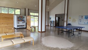 A spacious room with a ping pong table, a vending machine, and seating areas. - Kanaya Onsen Hotel Ginga Park Hanamaki (Hanamaki)