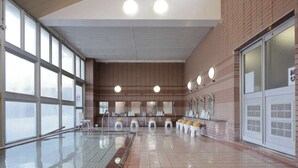 A swimming pool area with a tiled floor, benches, and a row of sinks. - Kanaya Onsen Hotel Ginga Park Hanamaki (Hanamaki)