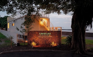 A modern building with a metal fence, a sign reading 'Thousand Garden,' and a view of the water. - Thousand Garden Tarumizu (Tarumizu)