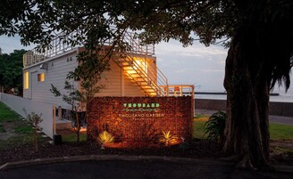 A modern building with a metal fence and a sign that reads "THOUSAND GARDEN".
