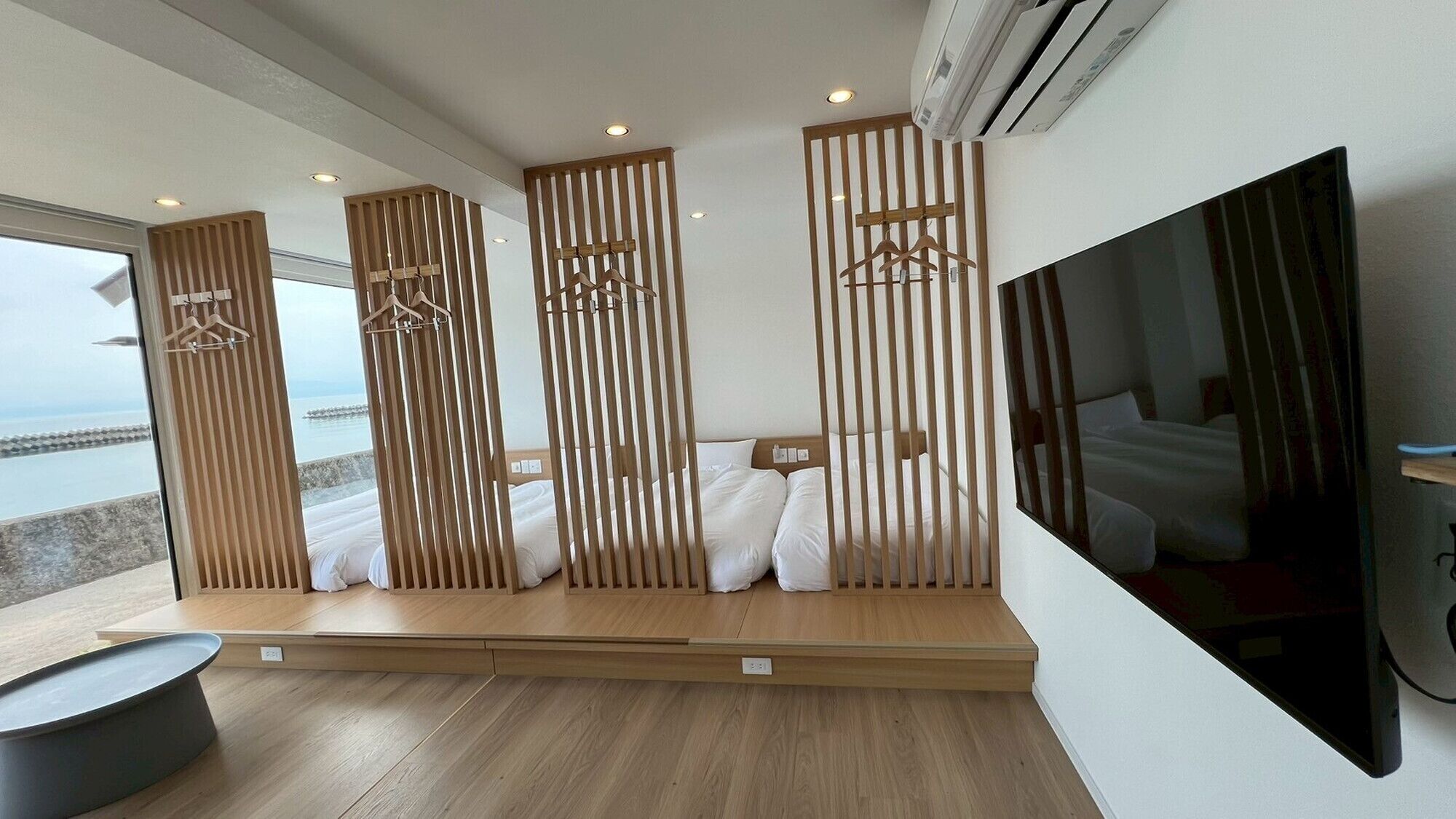 Habitación de hotel moderna con una cama grande, televisión y vista al mar.