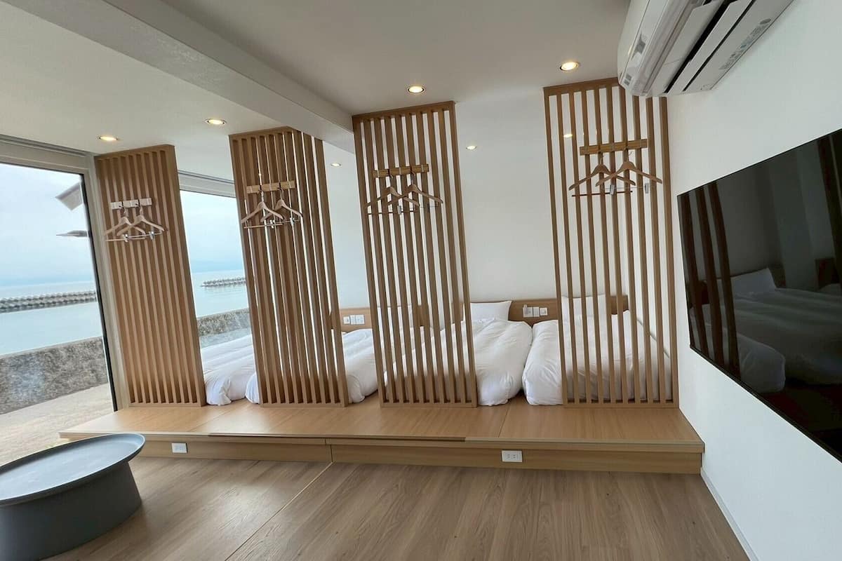 Habitación de hotel moderna con una cama grande, televisión y vista al mar.
