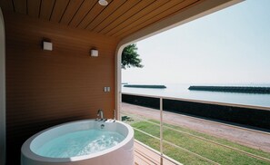 A spa room with a large bathtub, wooden ceiling, and a view of the sea. - Thousand Garden Tarumizu (Tarumizu)