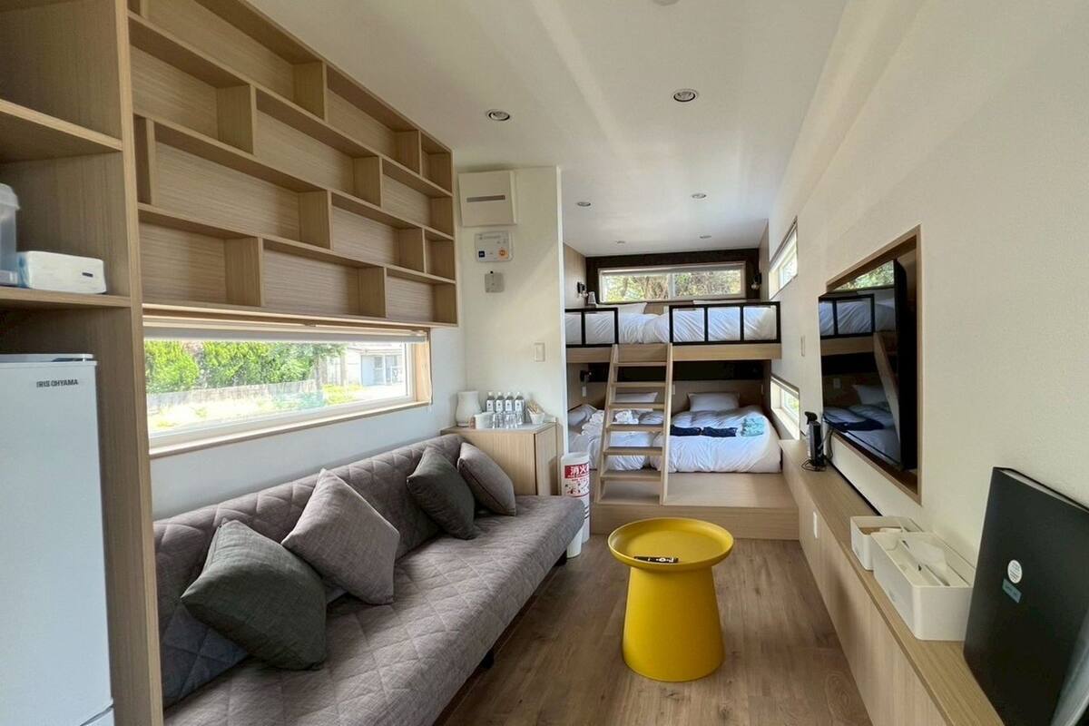 Habitación compacta y moderna con literas, un sofá y una mesita.
