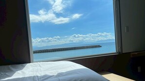 A room with a large window offering a view of a calm sea and a distant pier. - Thousand Garden Tarumizu (Tarumizu)