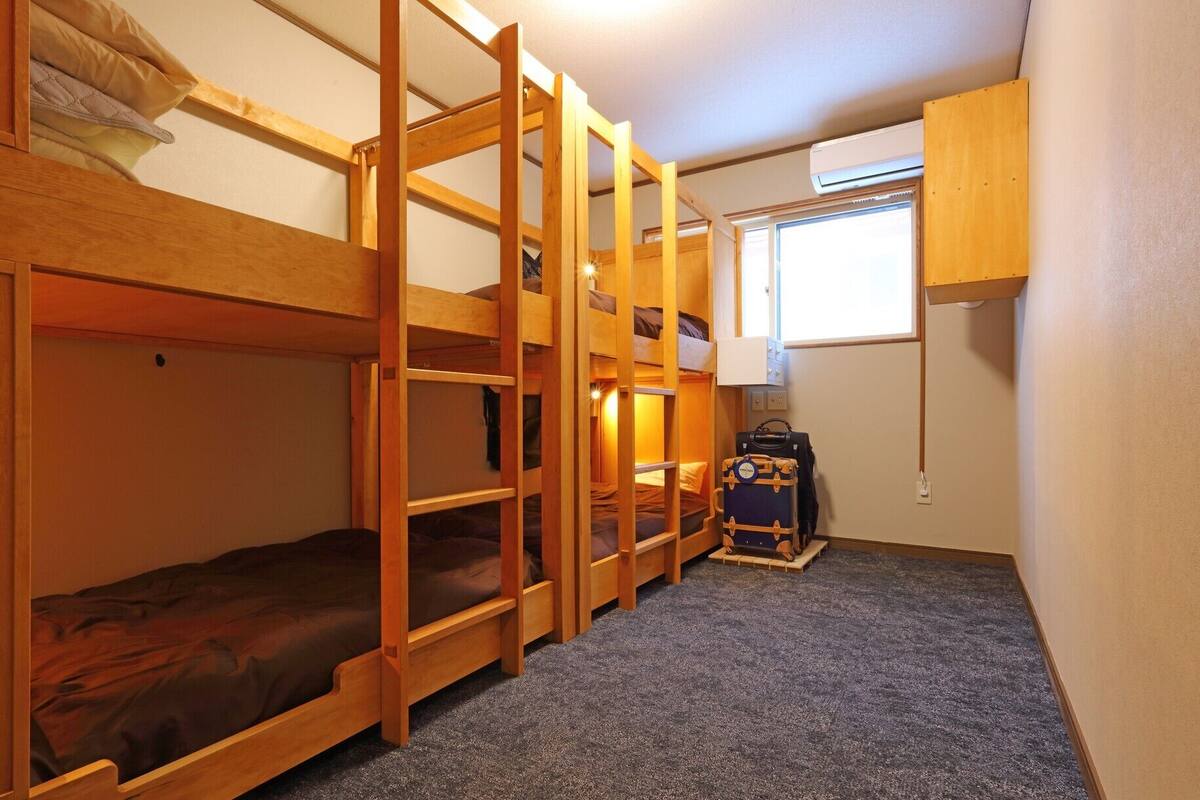 Een slaapkamer met een stapelbed, een koffer en een lamp.