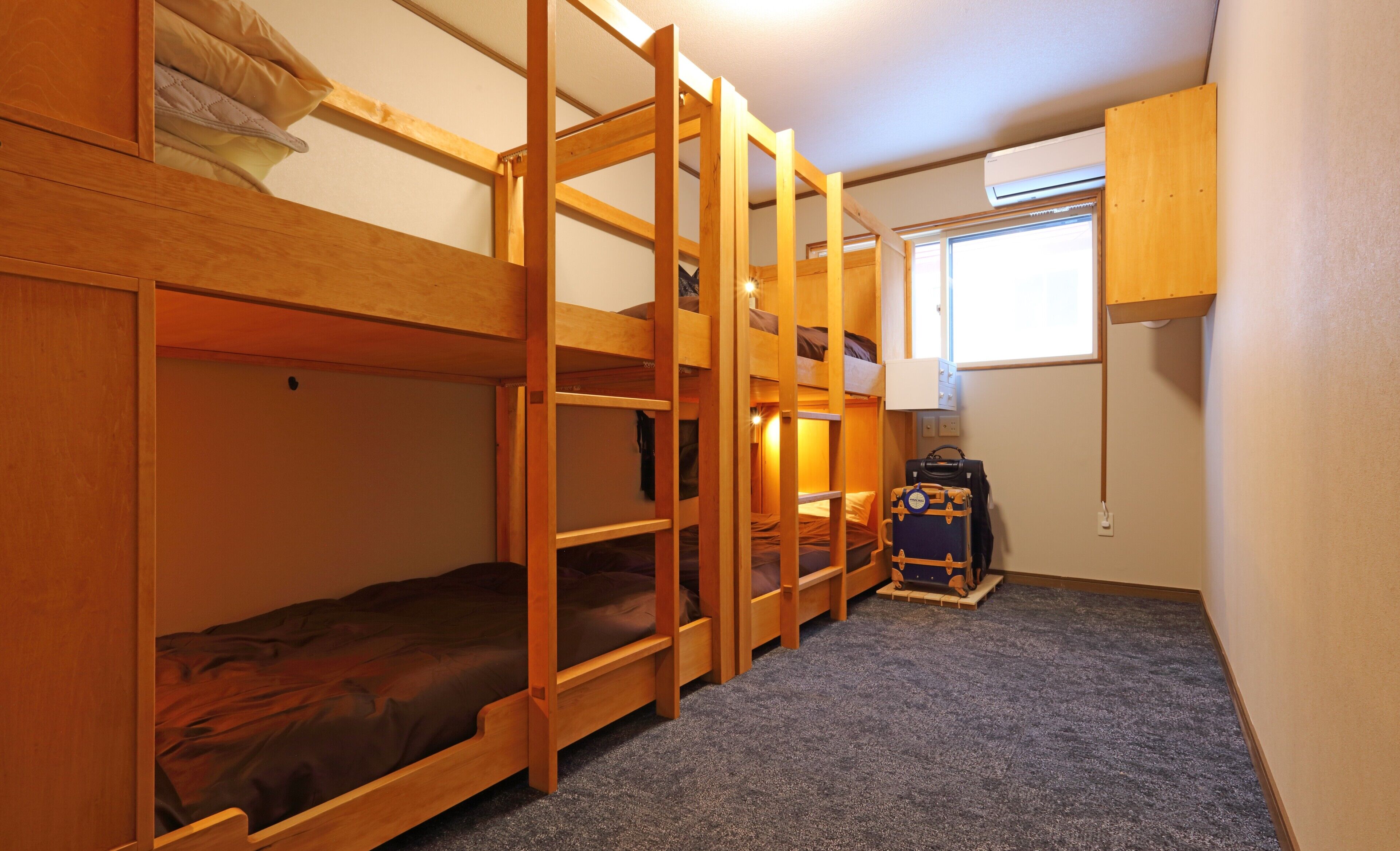 Une chambre avec un lit superposé, un petit bureau et une valise.