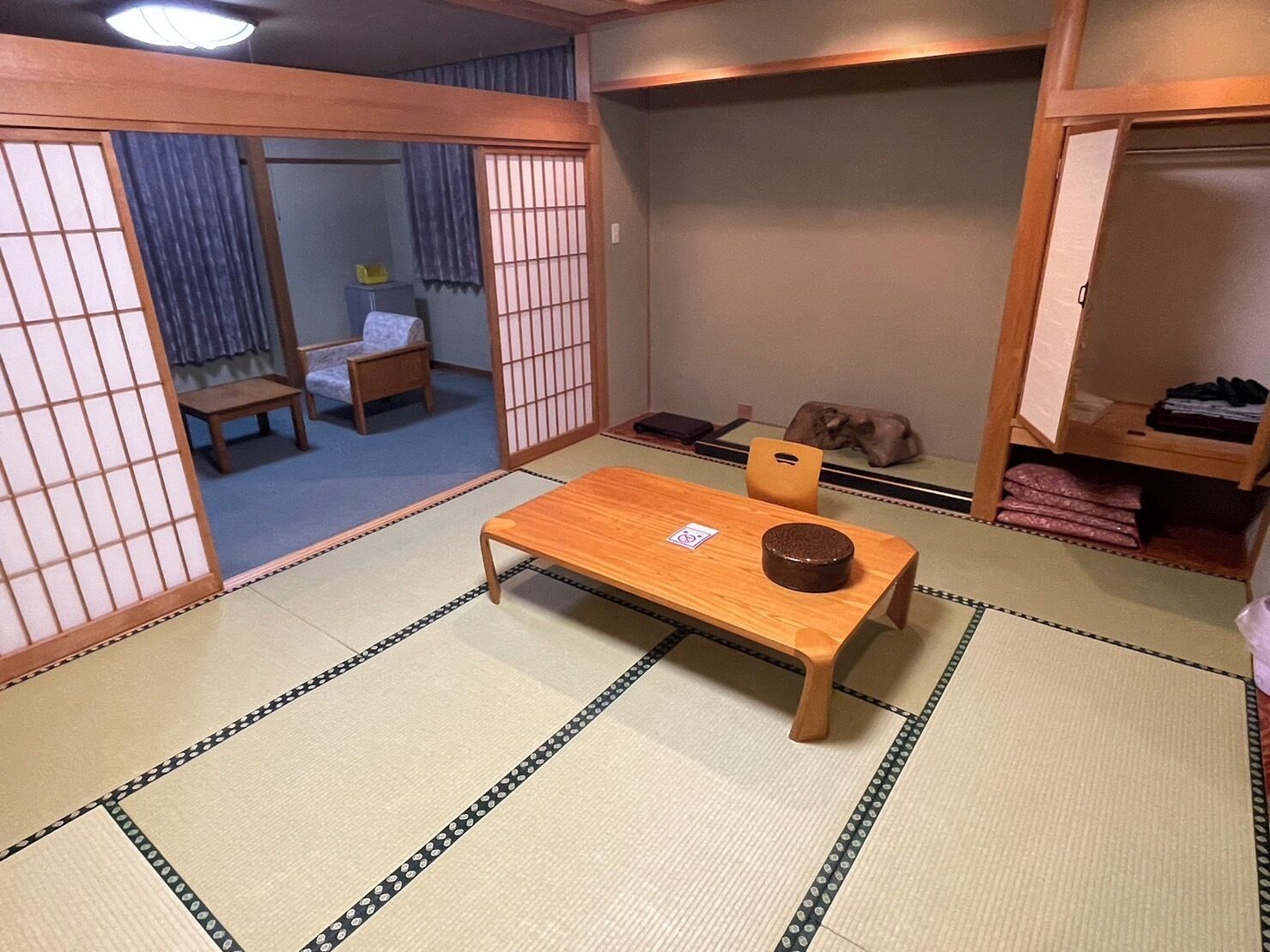 Ein traditioneller japanischer Raum mit Tatami-Bodenbelag, einem niedrigen Holztisch und einer Futonliege.