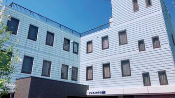 Un edificio de varios pisos con un diseño arquitectónico moderno, que presenta una combinación de estilos de ventanas y un techo plano.