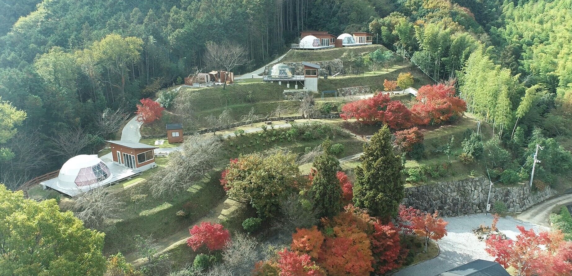 A hillside property with multiple buildings, including a large dome-shaped structure and several smaller houses.