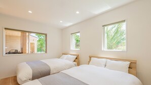 Habitación de hotel con dos camas, ventanas amplias y vistas al exterior.