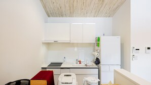 Cocina compacta con armarios blancos, horno empotrado, pileta y microondas. Cuenta con un pequeño comedor con mesa y sillas.