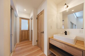 Een moderne badkamer met een houten wastafelmeubel, een grote spiegel en een witte wasbak.