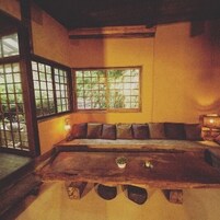 A traditional Japanese-style room with tatami flooring, a low wooden table, and a window with a view of greenery.