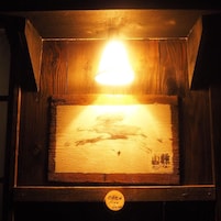 A wooden structure with a light fixture, a sign with 'OPEN 19:00 23:00', and some text in a foreign language.
