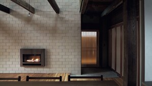 Een modern interieur met een open haard, houten balken en een bakstenen muur.