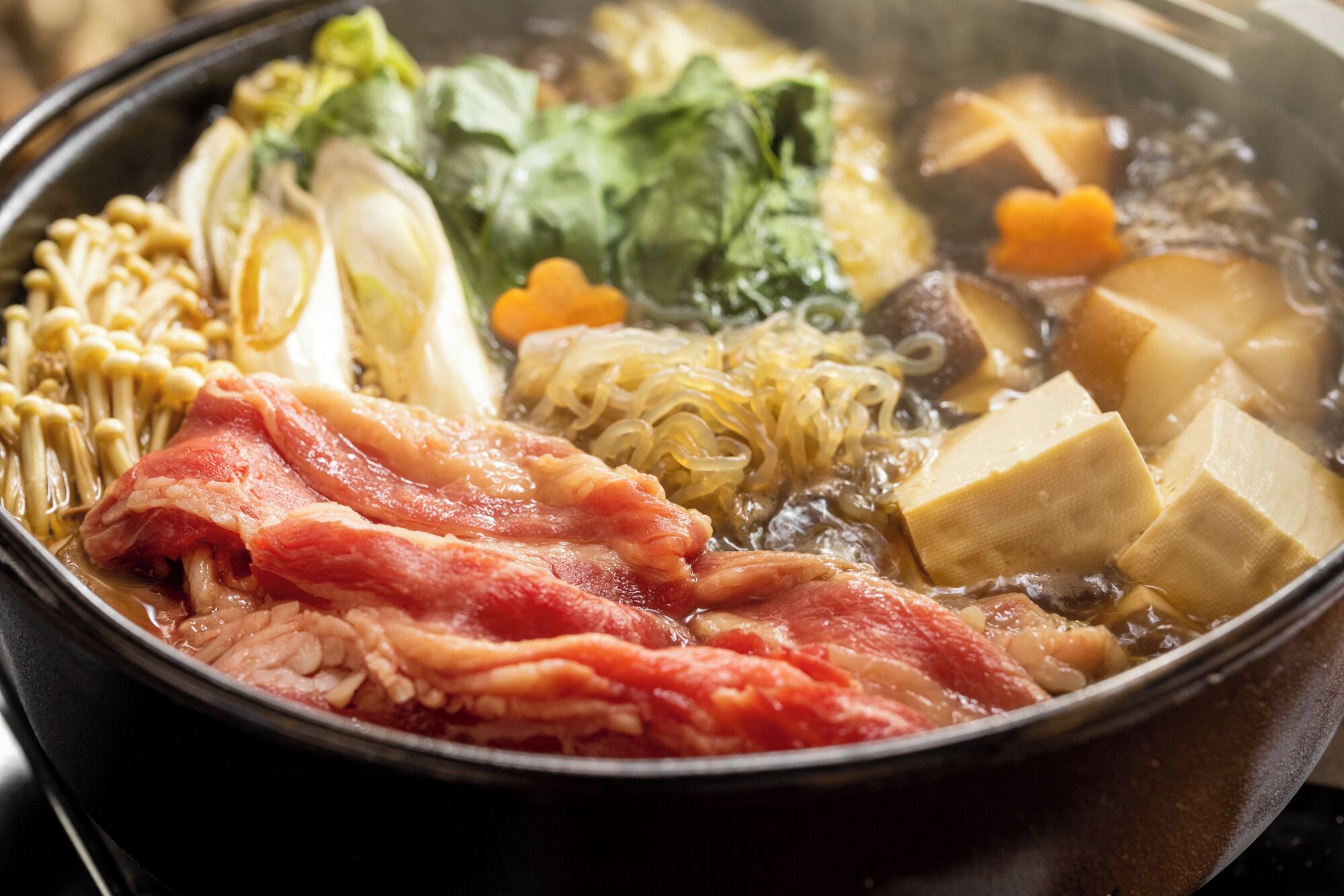 A hot pot with various ingredients like tofu, vegetables, and meat.