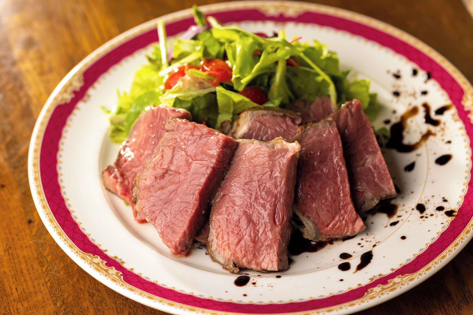 A plate with slices of meat and a salad.