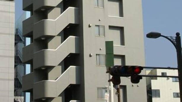 Ein hohes, modernes Gebäude mit mehreren Balkonen und einem Schild, das es als Hotel kennzeichnet.