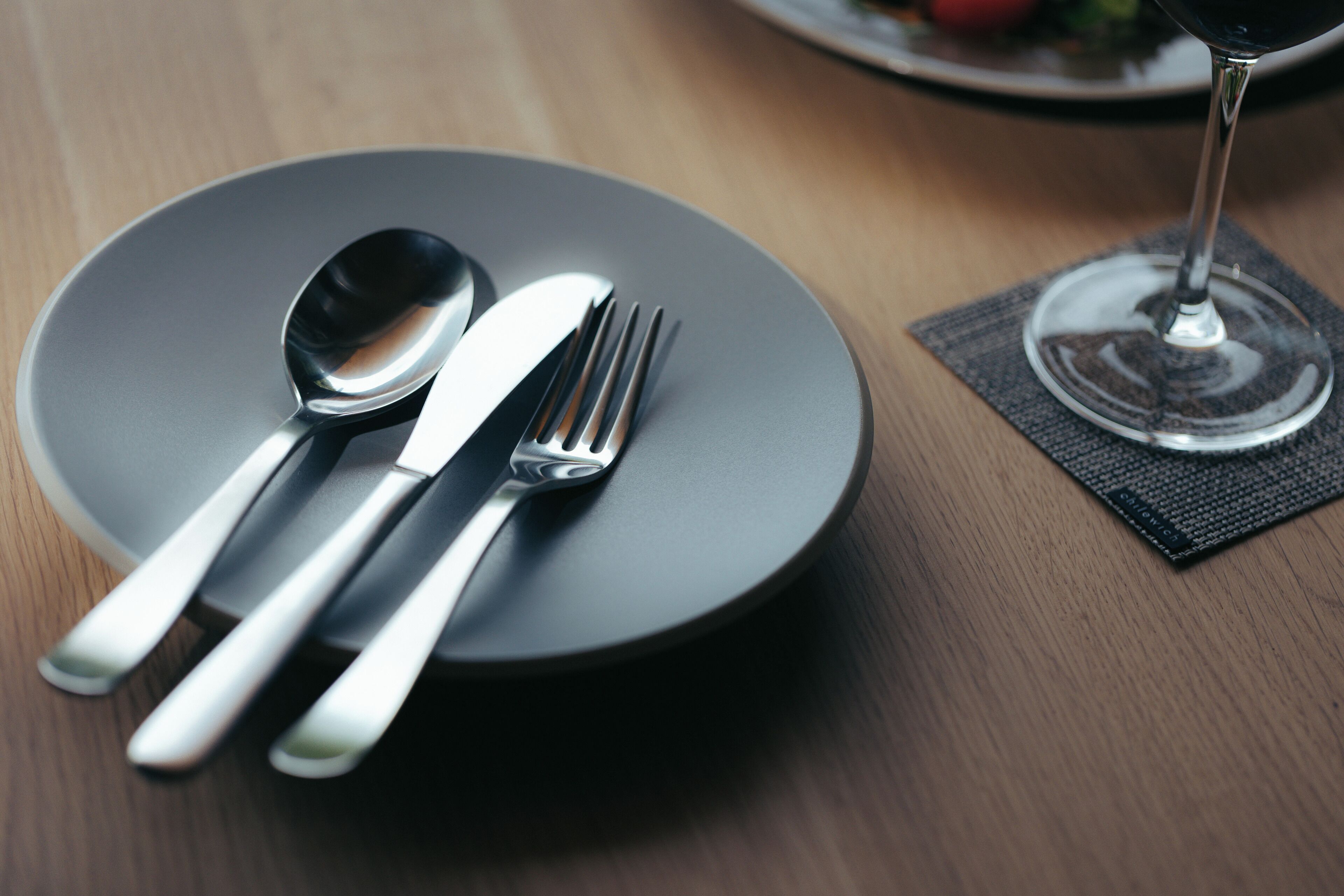 A dining table with a plate, cutlery, and a wine glass.