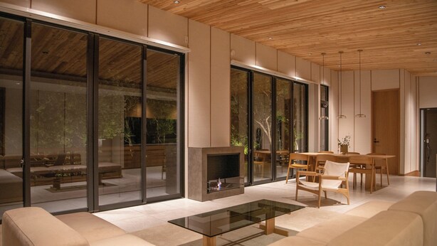 A modern living room with a glass coffee table, beige sofas, and a fireplace. - Soothe Forest (Awaji)