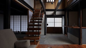 A traditional Japanese interior with tatami flooring, a low wooden table with a bowl and glass, a sofa, and a staircase with wooden railings. - Toutou Onzaki Machiya no Yado (Kurashiki)