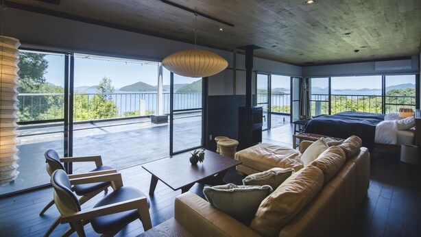 A modern room with a large bed, a sofa, and a dining area. It features large windows with a view of the mountains and a balcony. - Seki Syu Kan (Mitoyo)