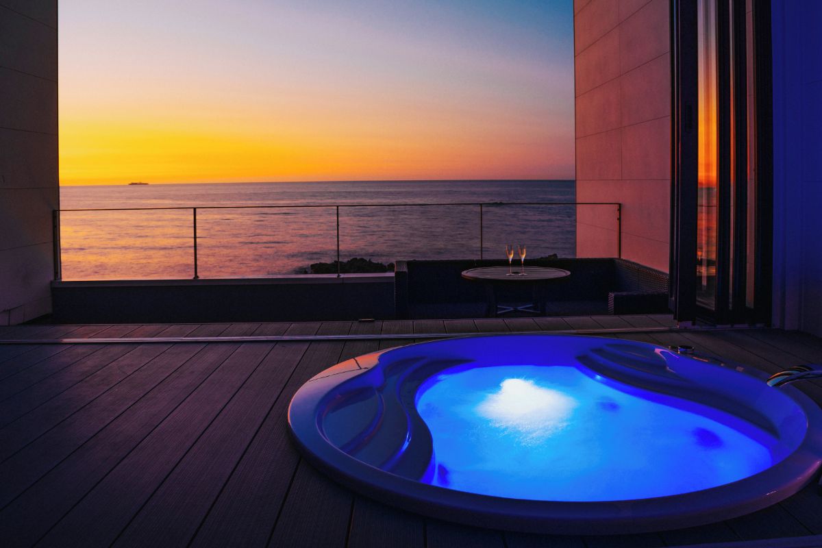 Un bain à remous sur une terrasse en bois, avec vue sur le coucher de soleil.