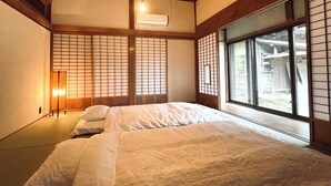 A traditional Japanese-style room with tatami flooring, a sliding shoji screen door, and a large window offering a view of the outside. - Sato no Yado Rishi (Isumi)