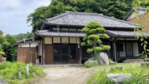 A traditional Japanese building with a tiled roof, wooden structure, and a well-maintained garden with rocks and a bonsai tree. - Sato no Yado Rishi (Isumi)