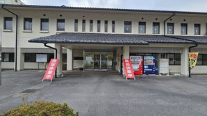 Een gebouw met een pannendak en meerdere ramen. Buiten staan borden in een vreemde taal en automaten.