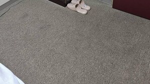 Een kleine, afgesloten ruimte met een bed, een bordje met gratis Wi-Fi, een deur en een paar slippers op de vloer.