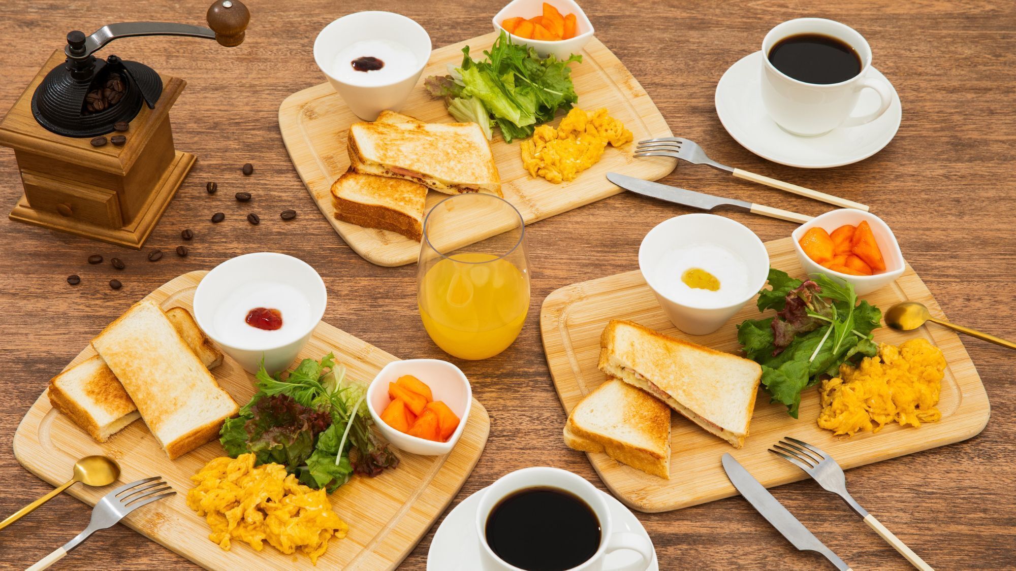 A wooden table with breakfast items including toast, scrambled eggs, and orange juice.