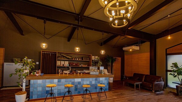 Un espace bar avec des tabourets, un comptoir et un luminaire suspendu.