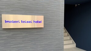 Letrero del hotel Imabari taisai con un moderno fondo de pared texturizado.