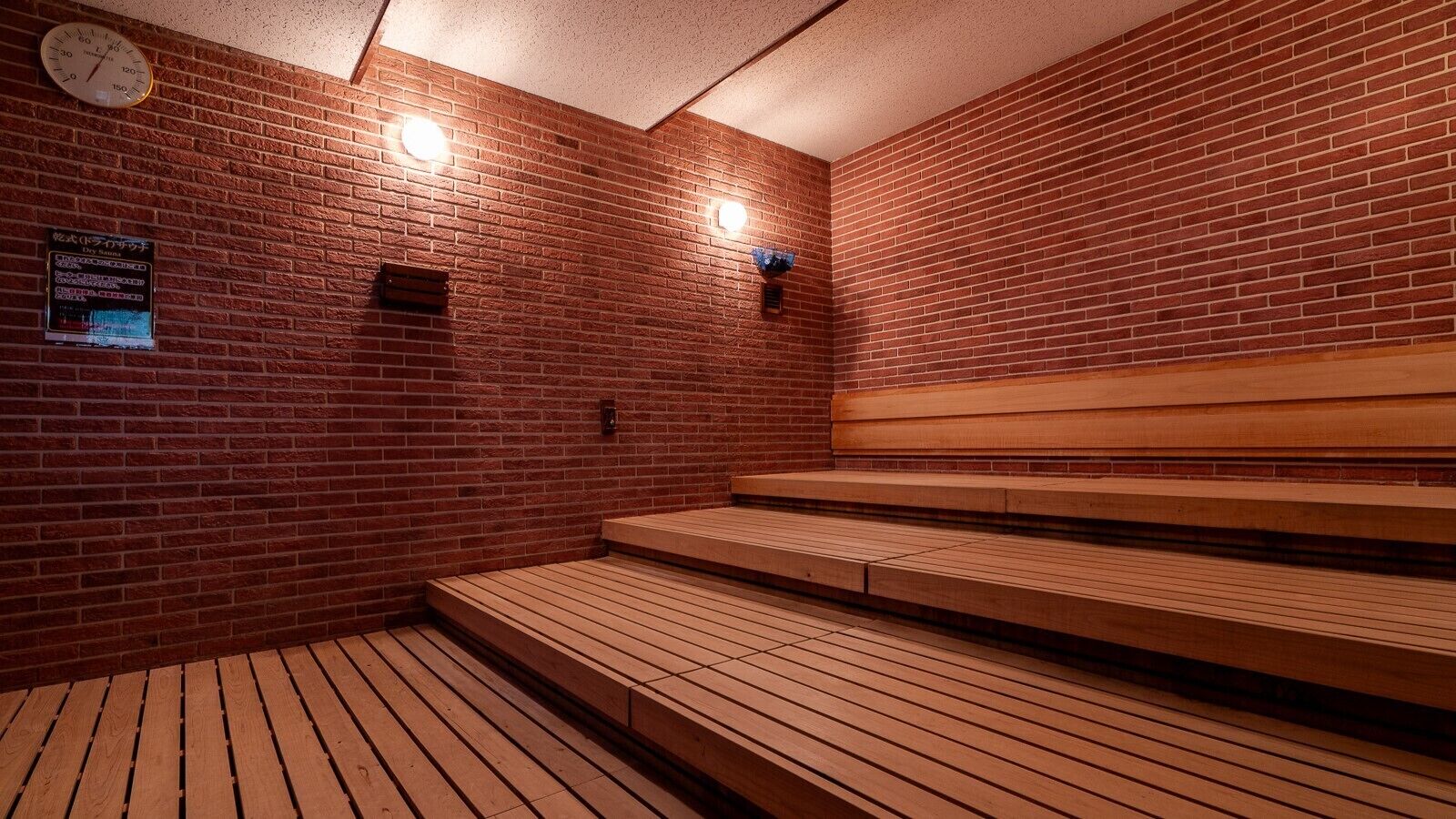 A sauna with wooden benches and a brick wall.