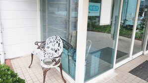 A white metal bench outside a building with a glass door and a sign in Japanese. - Youhuuminnsyuku Beisaidoinn Kushimotokan (Kushimoto)