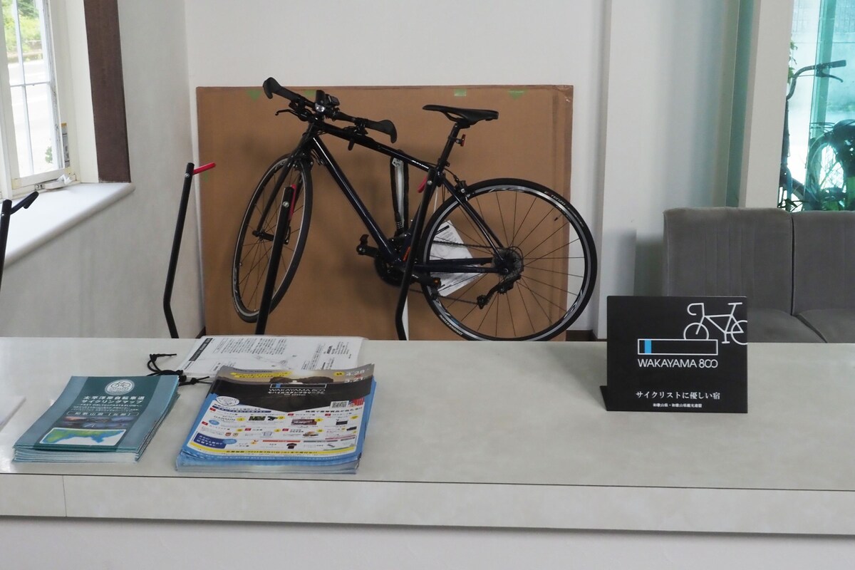 A reception desk with a bicycle, a sign for WAKAYAMA 800, and some brochures.
