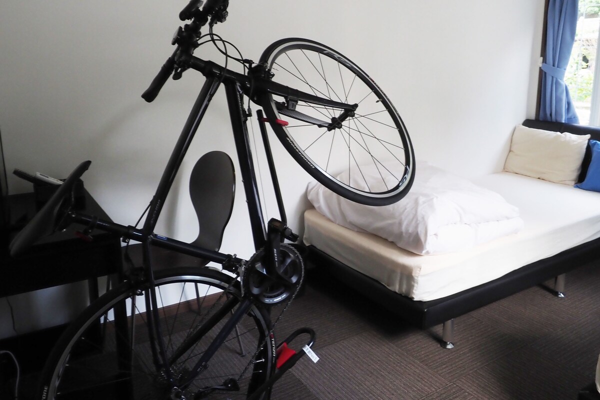 A room with a bed, a bicycle, and a window with curtains.