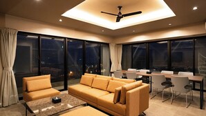 A modern hotel room with a sofa, coffee table, and dining area. - United Resort Chatan Ocean Front (Chatan)